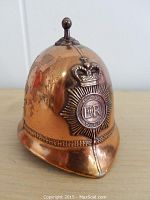 Front angled view of the copper bell shaped like a British police bobby hat showing the detailed police badge with crown and 'ER' insignia.