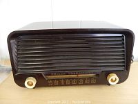 Front angled view of vintage Philco Transitone radio showing dark bakelite body and ivory tuning knobs.