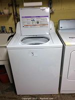 Front view of Amana top load washing machine with lid open.