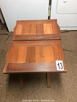Top-down view of one stained wooden side table showing rectangular top with wood panel design and crossed wood legs.