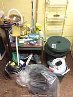 Overall view of pond supplies on and around small table showing buckets, pump, hose, filter pads, liner