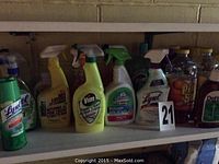 Shelf with various unopened cleaning supply bottles including Lysol, Vim, bathroom cleaner, and Dettol.