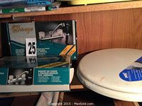 Two unopened kitchen deck faucets with spray nozzles in boxes labeled 'Duro' and one unopened white toilet seat in packaging.