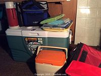 Photo of large 58 quart hard cooler, four soft fabric sided zippered coolers, and two thermoses.