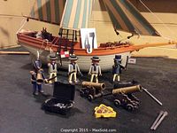 Wide view of wooden sailing ship with figures and accessories displayed on a table with numbered card showing '47'