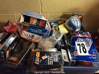 Photo showing assorted unopened medical braces, including Bike Pro Line ankle and elbow neoprene braces, and gloves in large packs.