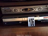 Close-up of Hitachi VHS DVD combo player with remote, showing front panel and control buttons, with a Cogeco unit on top not included.