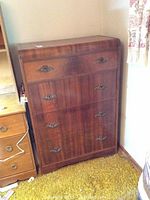 Front view of the tall boy dresser, showing all four drawers and ornate metal handles.