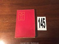 Red softcover book with gold embossed title 'Old Greek Folk Stories Peabody' placed on wooden table alongside lot number 145.