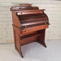 Front view of child-size oak roll-top desk showing two upper drawers, tambour top and lower shelf
