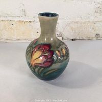 Front view of vase showing round body, flared neck, beige-to-teal glaze and red-yellow crocus design.