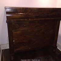 Front view of full dresser showing four drawers, bun feet and flame mahogany veneer