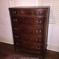Front view of antique dresser showing 5 drawers with brass hardware and wood veneer pattern.
