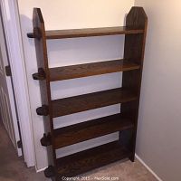 Front view of the antique Arts and Crafts solid oak bookcase showing four shelves and pegged side supports.