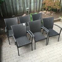 Six identical brown woven wicker outdoor armchairs arranged on a paved patio, showing front and side views.