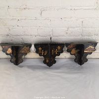 Three black lacquer folding shelves displayed open against a white brick background