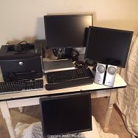 Full view of the computer lot including two Dell LCD monitors, Samsung LCD monitor, Bose speakers, Dell 1710 printer, and keyboards on the table.