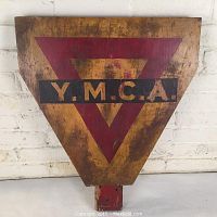 Front view of triangular wooden YMCA sign with red triangle and YMCA letters on a black strip.