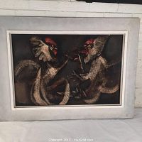 Frontal photo of the oil painting showing two fighting cocks in a white wooden frame against a white background.