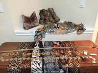 Photo showing two animal print handbags, a multi-colored scarf, multiple belts with gold-tone circular accents and various animal print scarves including leopard and tiger patterns.