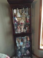 Full front view of curio cabinet showing both upper and lower display sections, carved top, and glass doors.