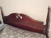 Close-up showing the wooden carved headboard with finial post on side of the bed frame.