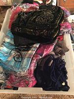 Bin containing a variety of colorful scarves, neatly stacked with different patterns and fabrics.