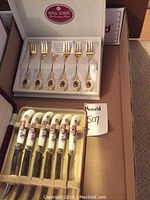 Set of six Royal Albert gold-tone forks with floral decorated handles in original box.