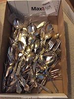 Box of assorted electroplated flatware showing forks, spoons, knives and a ladle