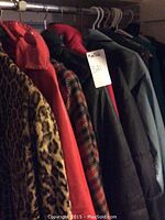 View of multiple ladies plus size coats including leopard print, red puffer, plaid, and others hanging on a rack.