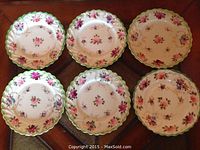 Overview of the six Nippon bone china dessert plates showing variety in floral patterns with scalloped edges and gold accents.