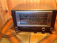 Front view of Hellicrafters Model 5R10A vintage radio sitting on a wooden surface, showing black casing with ventilation holes and front tuning dial with two control knobs.