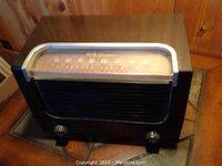 Front quarter view of vintage RCA Victor Model 2X61 radio showing wood casing, speaker grill, and control knobs.