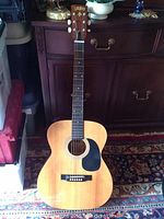 Full front view of natural wood finish acoustic guitar with black pickguard and six strings