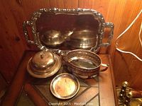 Photo showing entire 5-piece silver plated lot on wooden surface, including tray, basket, covered dish, lidded bowl, and small tray