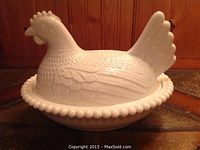 Photo of vintage milk glass nesting chicken covered dish showing side view on a tiled surface.