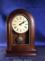 Front view of wooden Bulova mantel clock showing Roman numeral dial and pendulum.