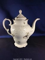 Full view of white porcelain tea pot with lid, showing overall shape and handle.