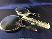 Full vanity set of hand mirror, hairbrush, and comb on dark background showing overall condition and arrangement.