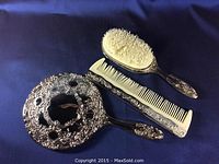 Vanity set showing hairbrush, comb, and filigree back of hand mirror, highlighting vintage condition and designs.