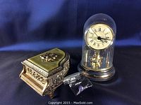Both Japanese style ornate music box and glass dome clock shown together on dark blue cloth.