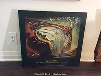 Framed Salvador Dalí print leaning against wall, showing complete artwork and frame.