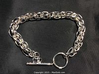 Silver chain bracelet laid out flat on black fabric background showing full length and clasp mechanism.