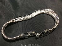 Full view of the sterling silver bracelet laid flat showing its snake chain style and clasp.