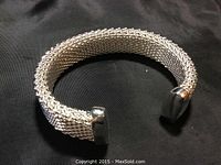 Sterling silver mesh cuff bracelet on black fabric background, showing overall design.