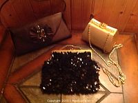 Lot of 3 vintage evening purses on display showing all three bags together in a corner with wood paneling background.