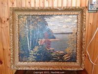 Front view of the antique oil painting showing a lakeside landscape with trees in fall colors and a textured carved wooden frame.