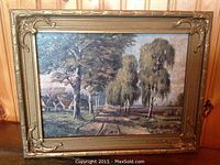 Full view of framed vintage print showing tree-lined country road with houses and ornate wooden frame.
