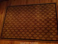 Full view of the rectangular wool area rug on hardwood floor showing the basketweave pattern and dark brown border.