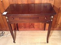 Front view of vintage side table showing drawer fronts with two wooden knobs, slatted detail, and metal decorative accents on legs.